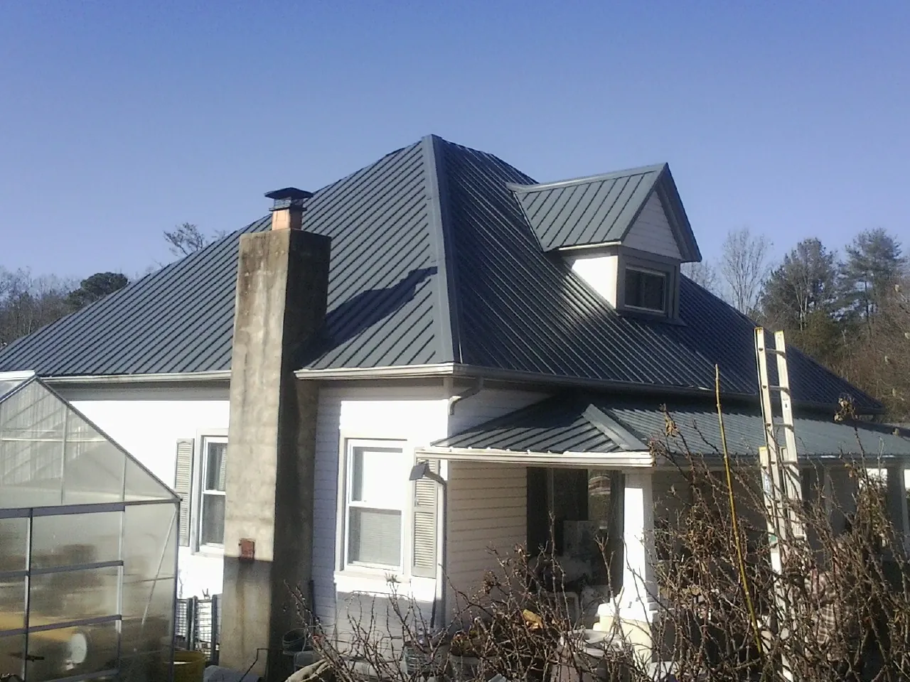 Dark blue standing seam metal roof on a white farmhouse with dormer — Slate & Tile Roof Repair by Roofing Brothers in Union
