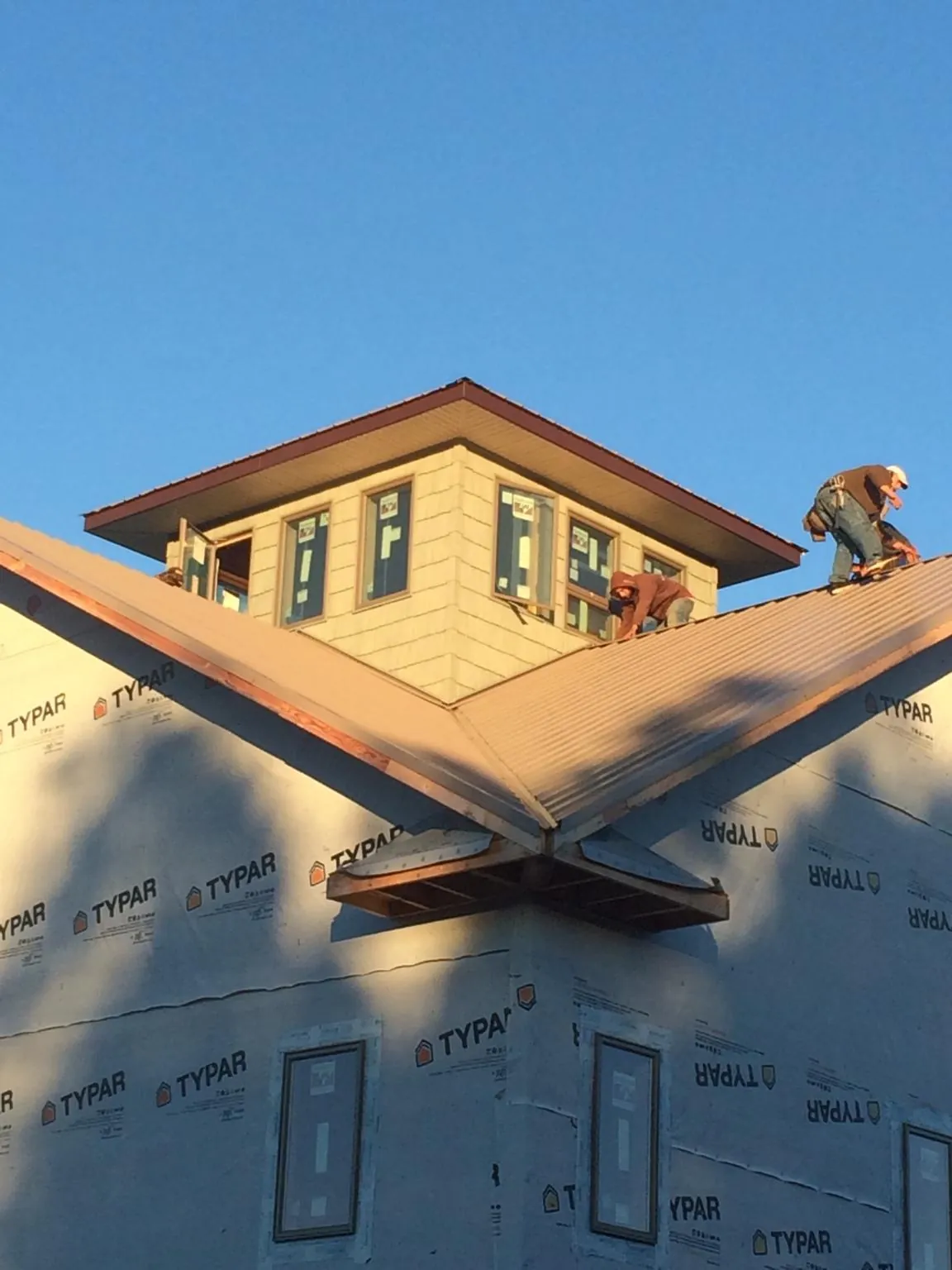 Roofers working around a rooftop cupola on a new metal roof at sunset — Roof Waterproofing in Union by Roofing Brothers